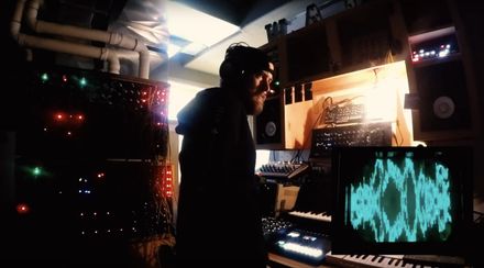 a rather confused heckseven standing in front of poorly-crafted synthesizers